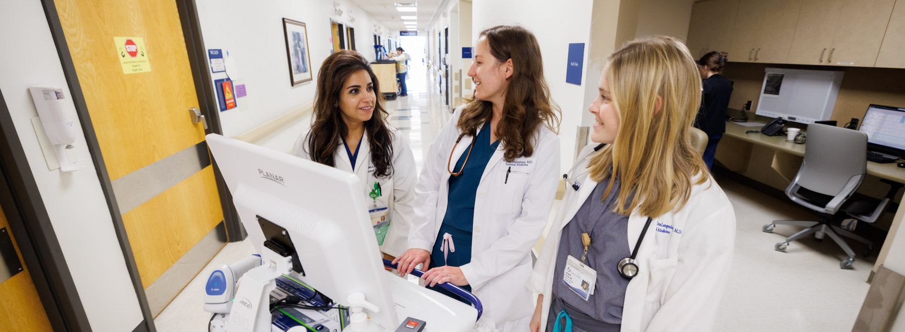 Three hospitalists interact while charting a patient encounter.